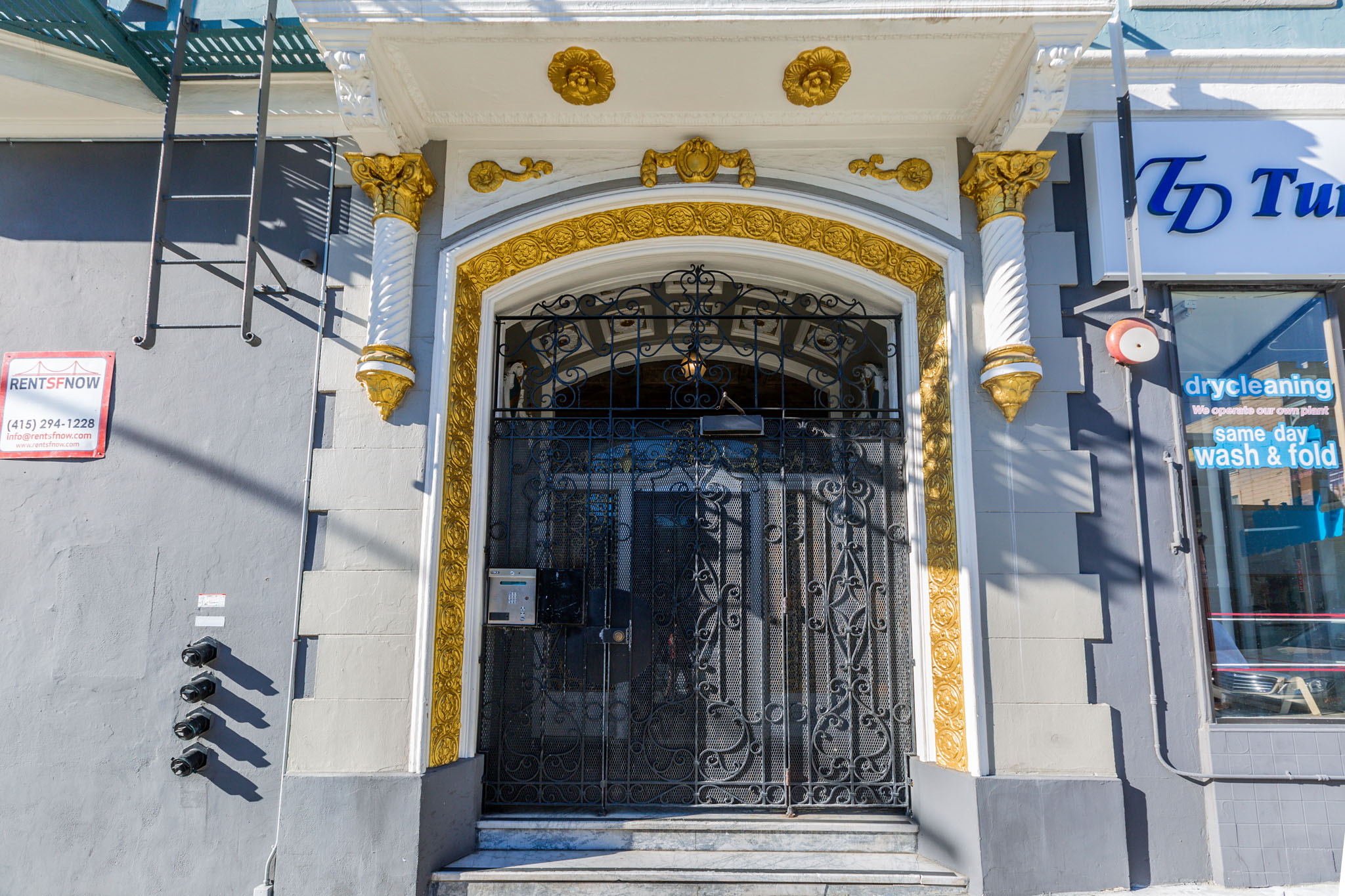 A grey building with a black door and gold trim.