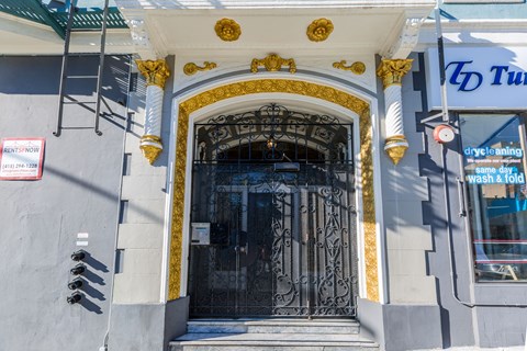 A grey building with a black door and gold trim.
