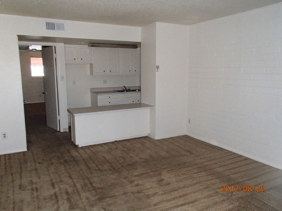 an empty living room with a kitchen in it