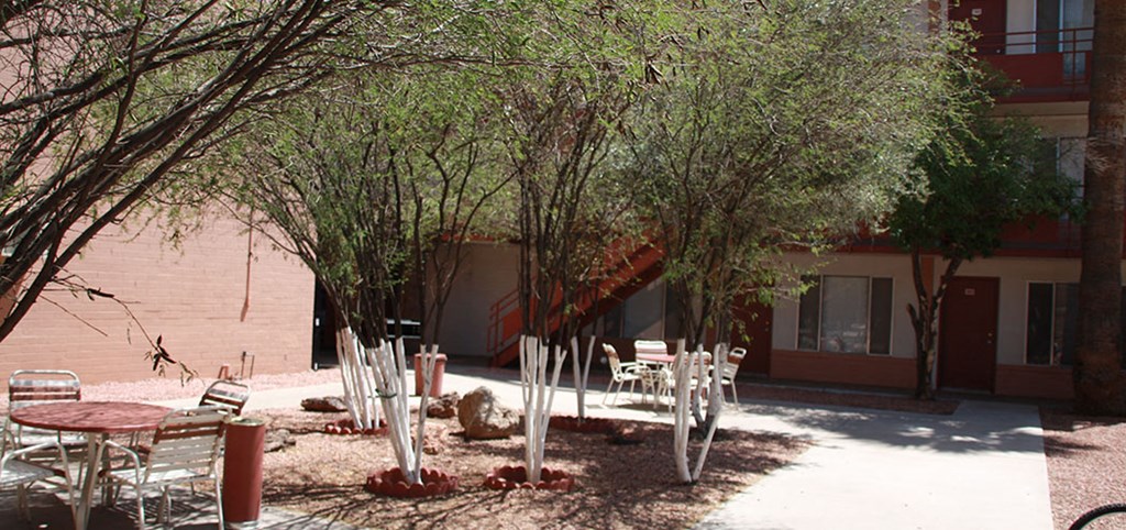 a courtyard with tables and chairs in front of a building