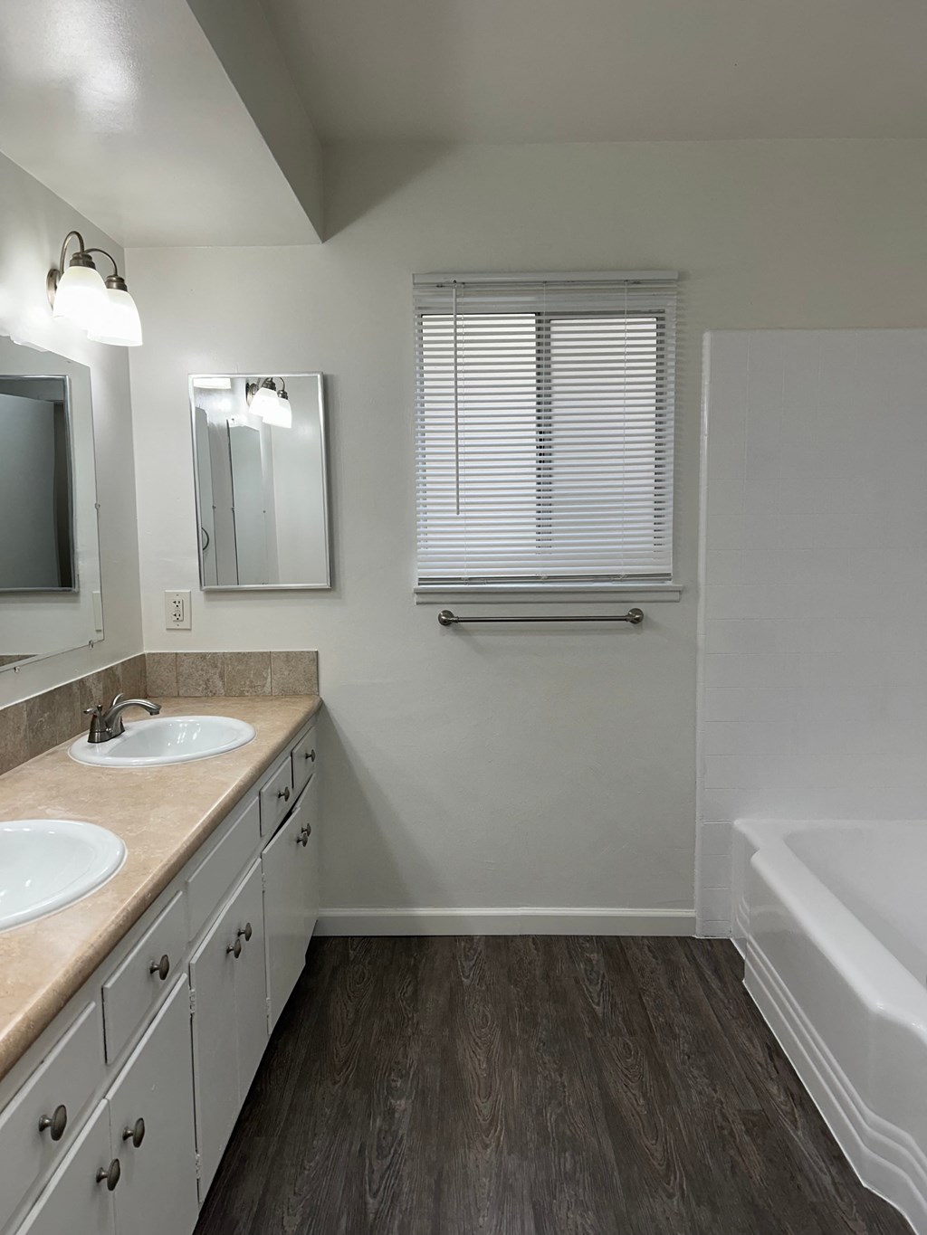 A white bathroom with a double sink and a white tub.