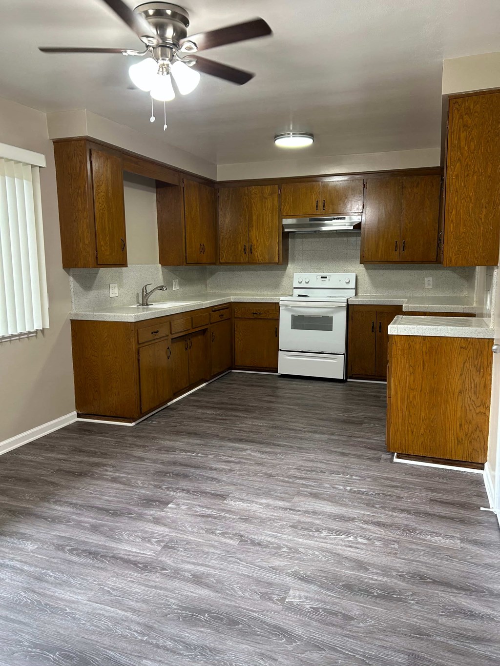 A kitchen with wooden cabinets and a white stove top oven.