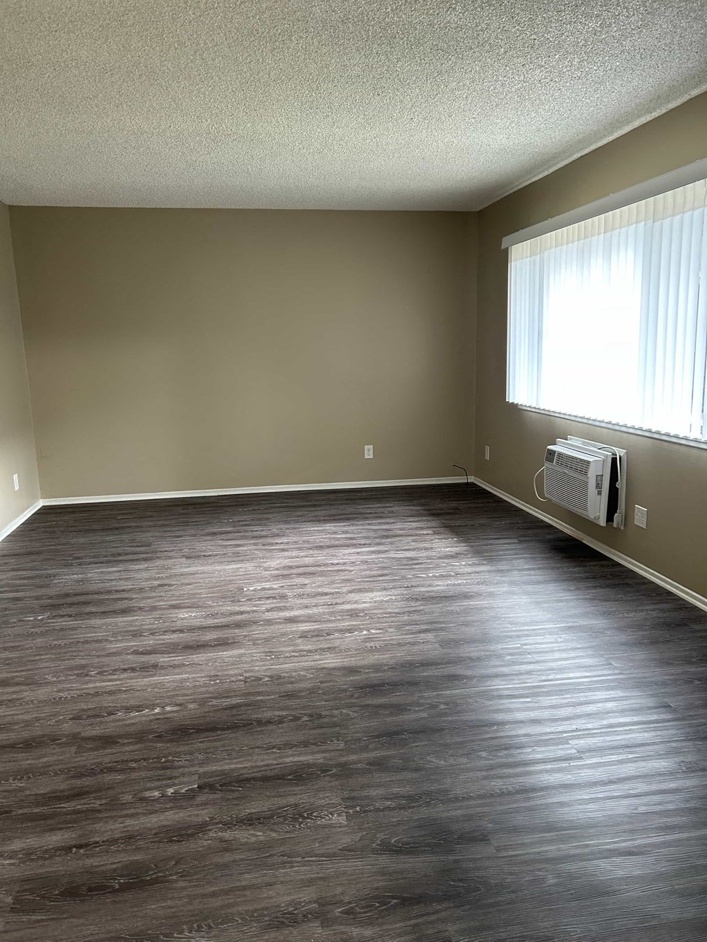 A room with a window and a wall-mounted air conditioner unit.