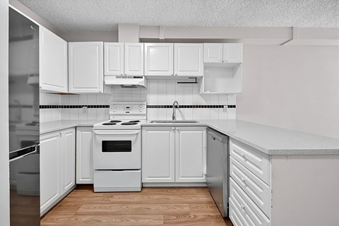 A white kitchen with a stove and a refrigerator.