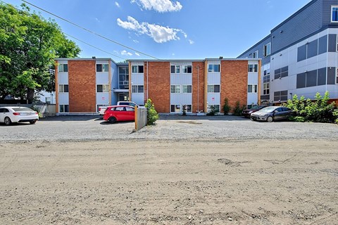 A red car is parked in front of a brick building.