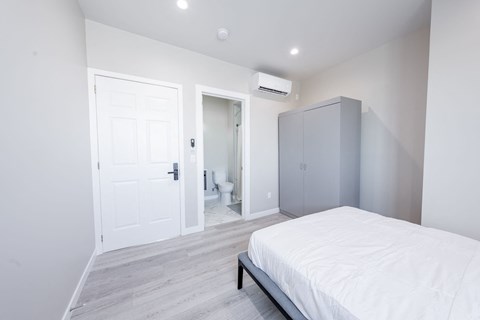 a white bedroom with a white bed and a gray closet