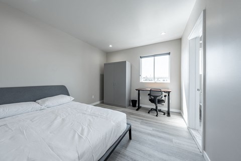 a bedroom with a bed and a desk and a window