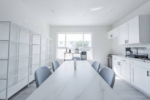 a white kitchen with a white table and white cabinets