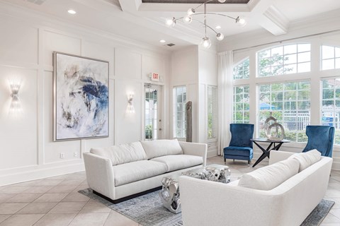 A living room with a white couch and a large abstract painting on the wall.