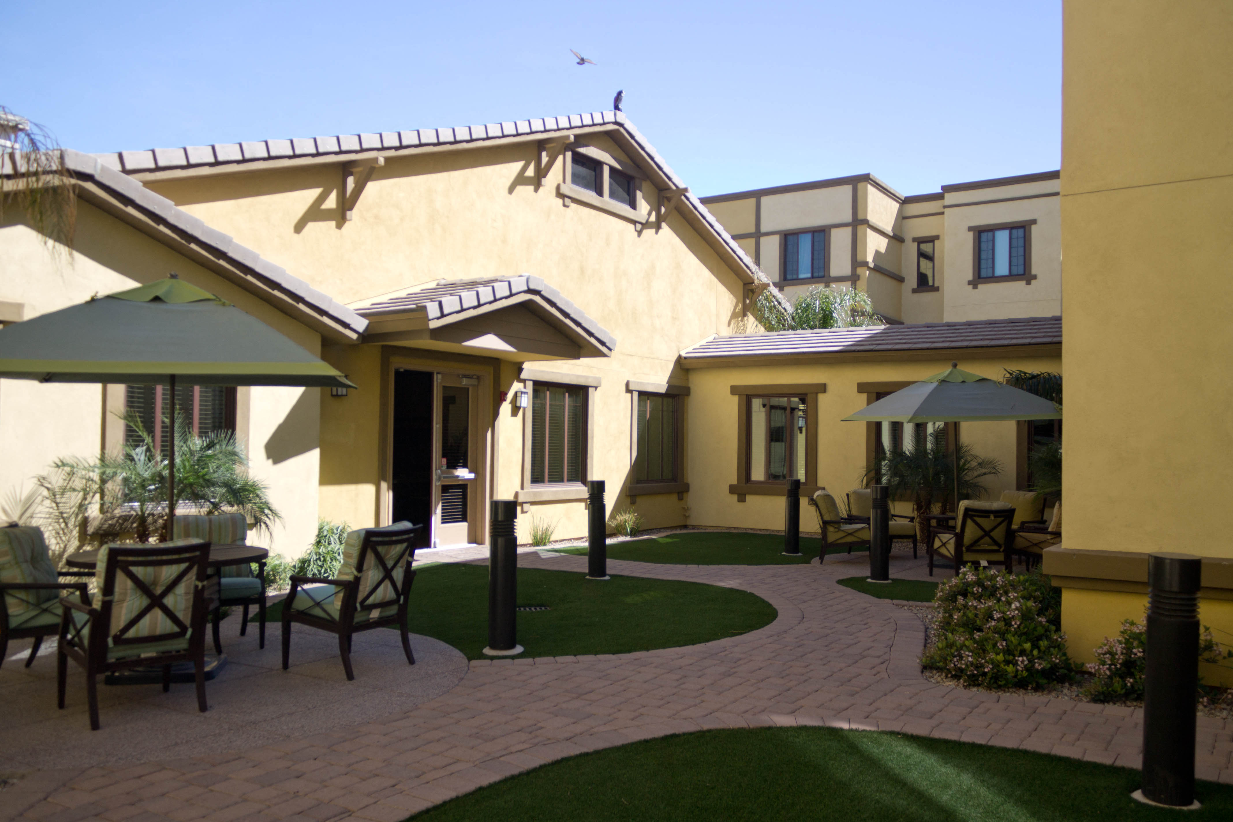 a patio with tables and chairs in front of a house