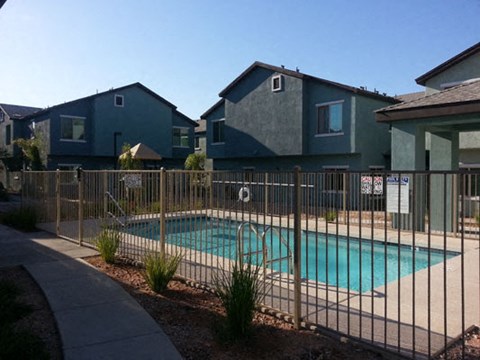 a swimming pool behind a fence in front of houses