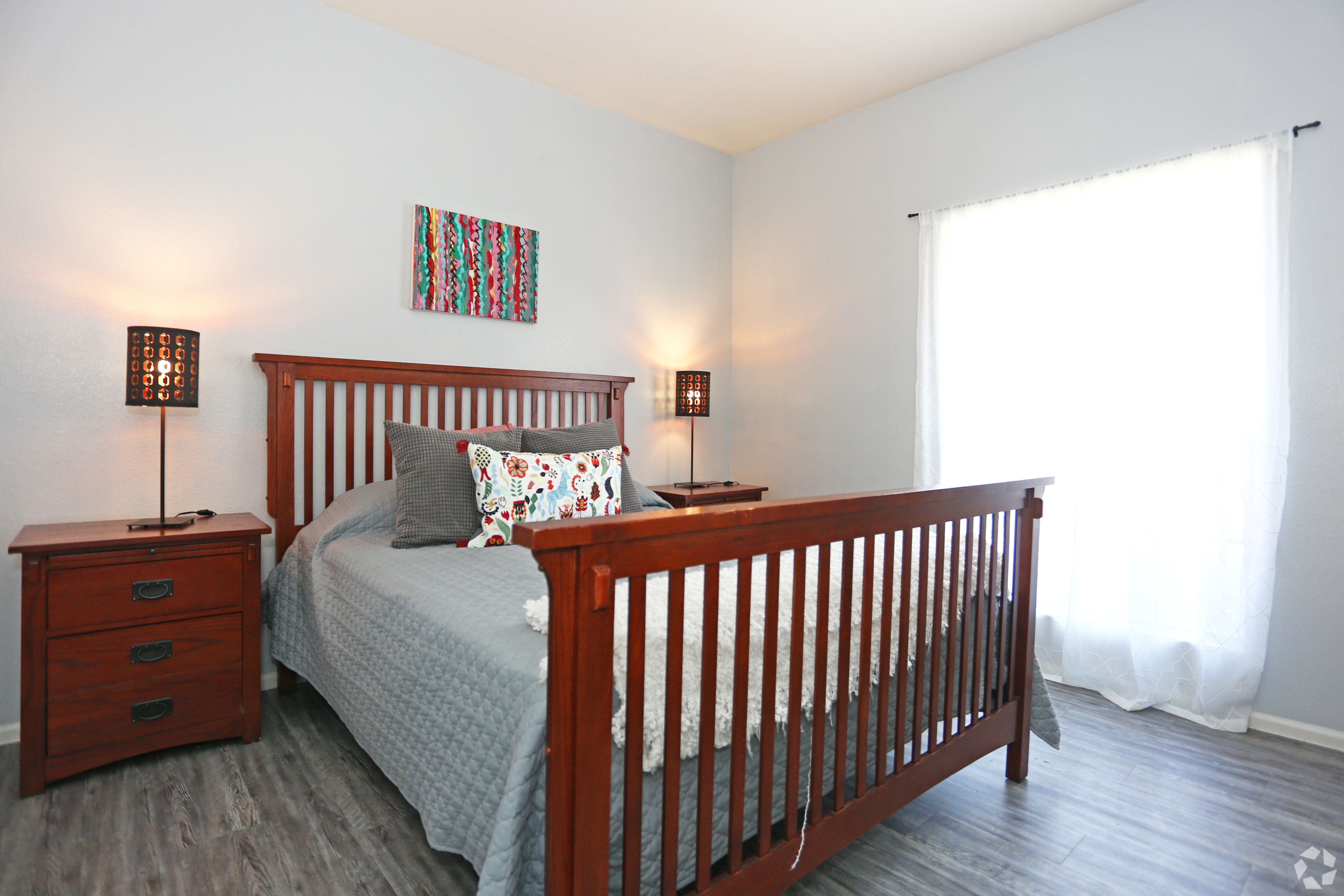 A bedroom with a bed, nightstand, and lamp.