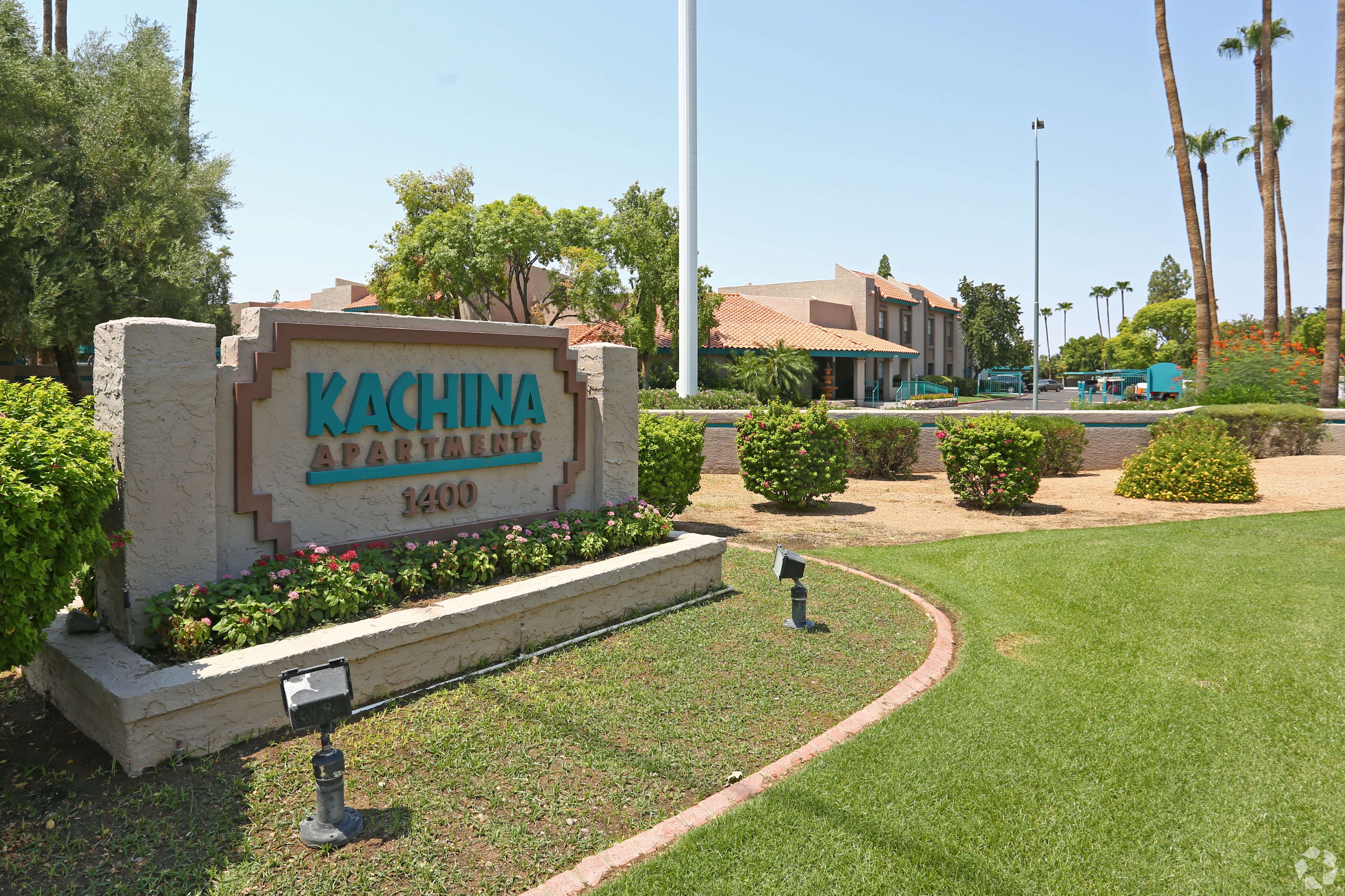 A sign for Kachina Apartments is in front of a building and palm trees.
