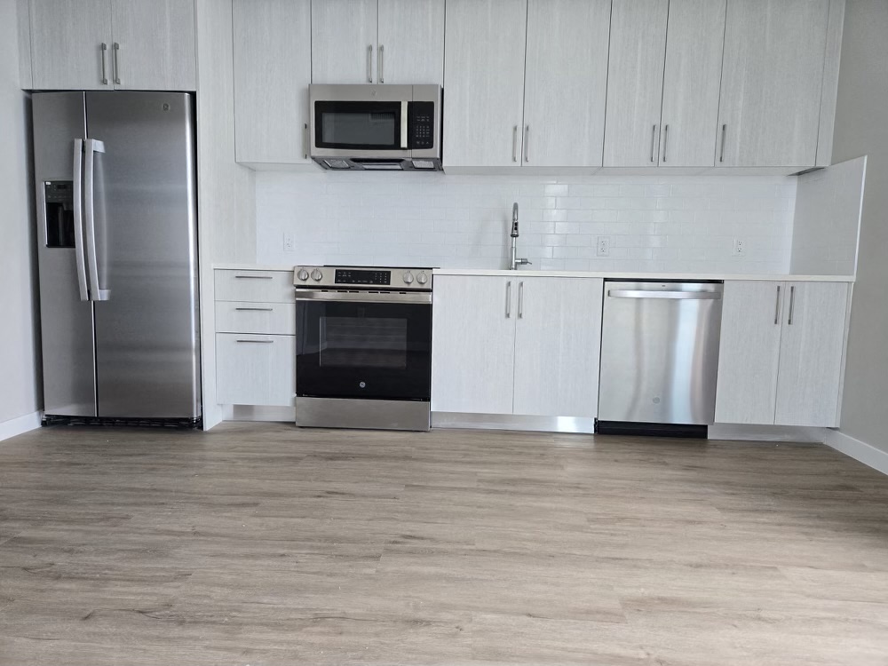 A kitchen with a refrigerator, oven, microwave, and dishwasher.