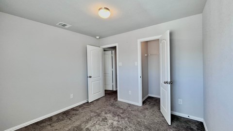 a bedroom with a carpeted floor and a door to a closet