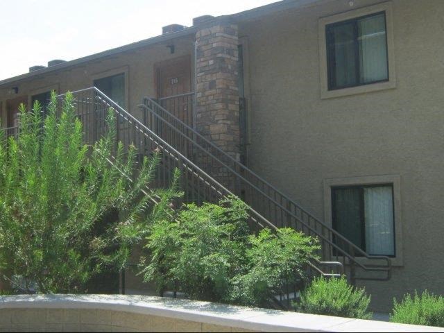 a building with stairs and a balcony and trees