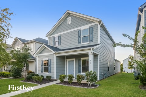 a home with blue siding and a green lawn and trees