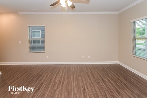 an empty living room with wood floors and a ceiling fan