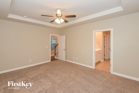 a master bedroom with a ceiling fan and a carpeted floor