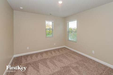 a empty room with carpet and two windows