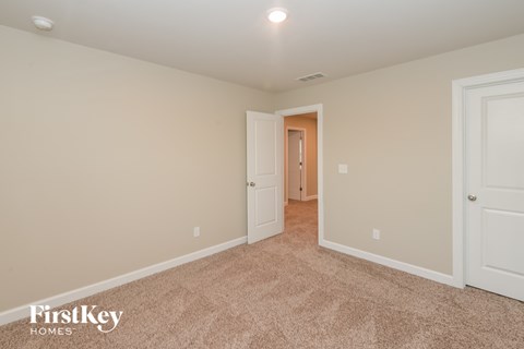 a bedroom with a carpeted floor and a door to a hallway