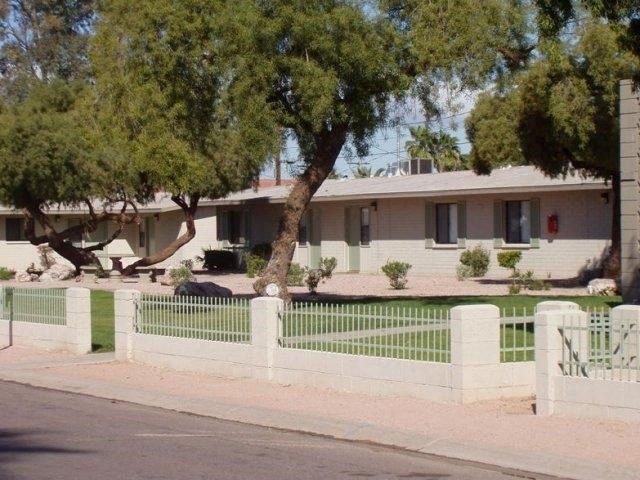 a house with a white fence and trees in front of it