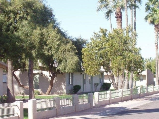 a white house with trees and a white fence