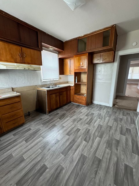 an empty kitchen with wooden floors and wooden cabinets