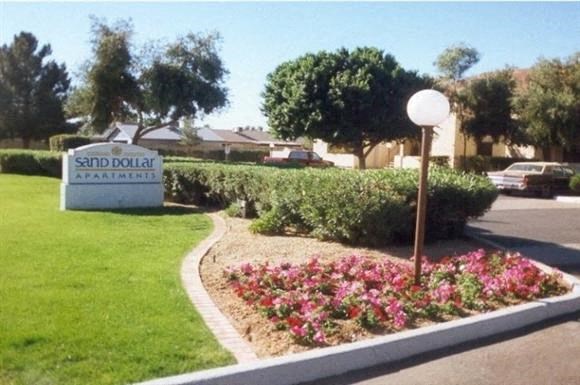 a park with a sign and a flower garden
