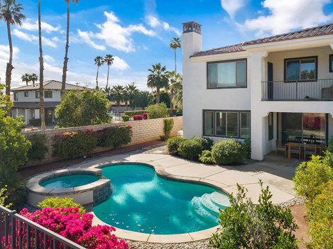 a backyard with a pool and a house with palm trees