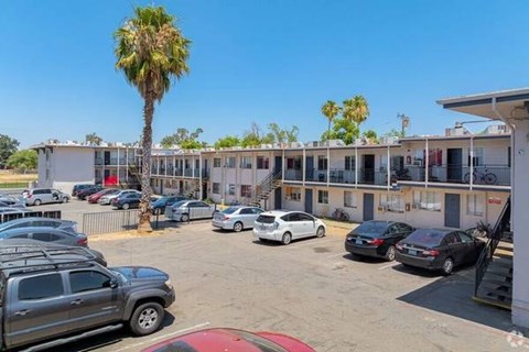 A parking lot with several cars and a building in the background.
