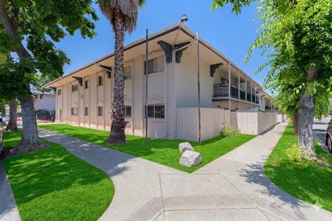 A building with a white fence and a green lawn in front.