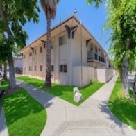A building with a white fence and a green lawn in front.