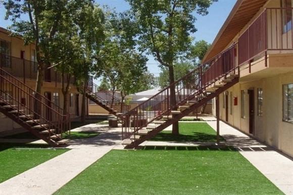 a building with stairs and green grass and trees