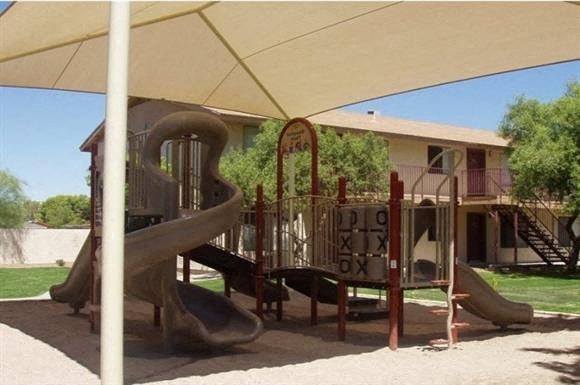 a playground with a slide and other toys in front of a house