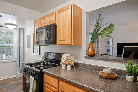A kitchen with a black stove top oven and wooden cabinets.