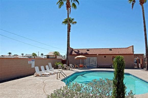 a swimming pool with chairs and a palm tree