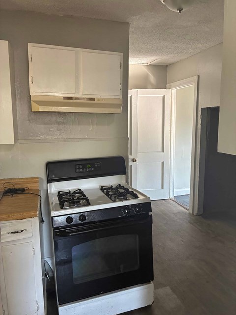 A black and white stove in a kitchen with a white cabinet above it.
