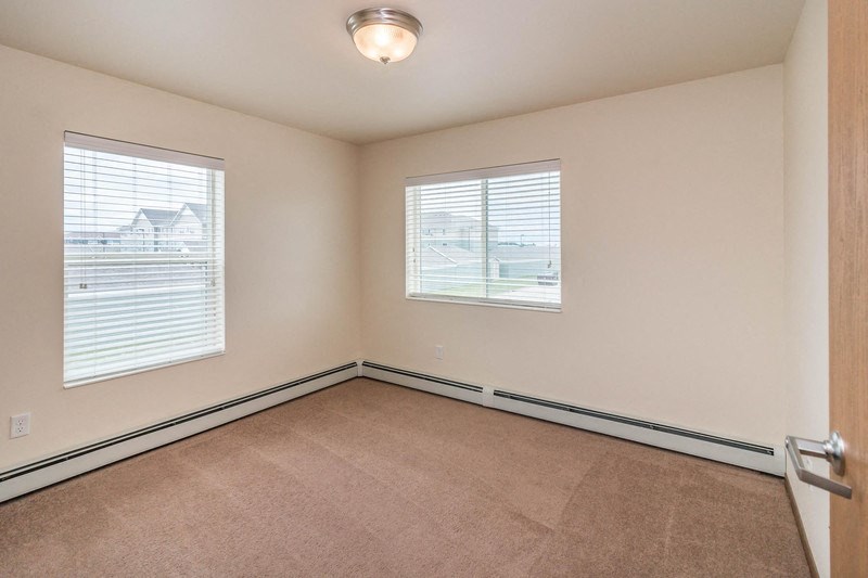 an empty room with two windows and a door