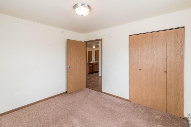 an empty living room with a closet and a door to a bathroom