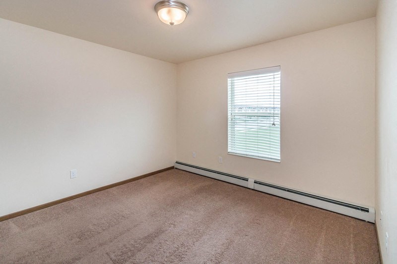 an empty living room with a window and carpet