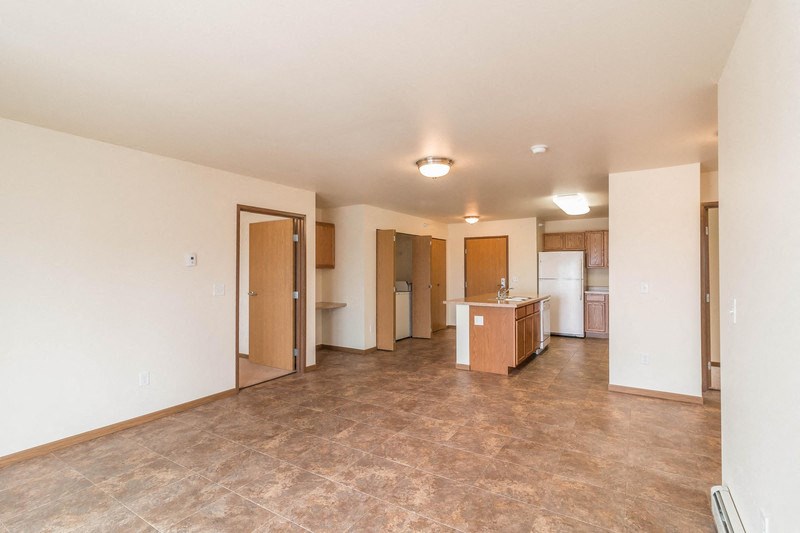an empty living room and kitchen with a tile floor