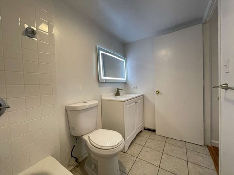 a white bathroom with a toilet and a window
