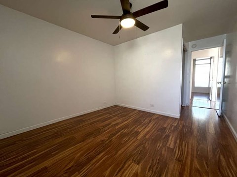 an empty living room with wood floors and a ceiling fan