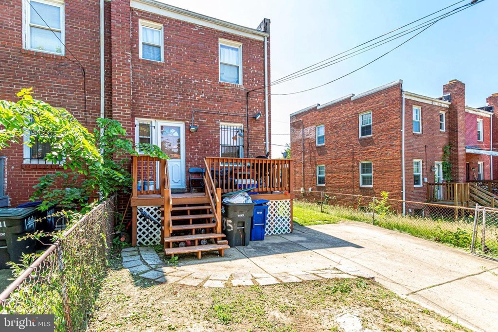 A red brick building with a wooden deck and a blue trash can.