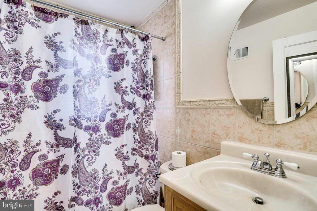 A bathroom with a purple and white shower curtain.