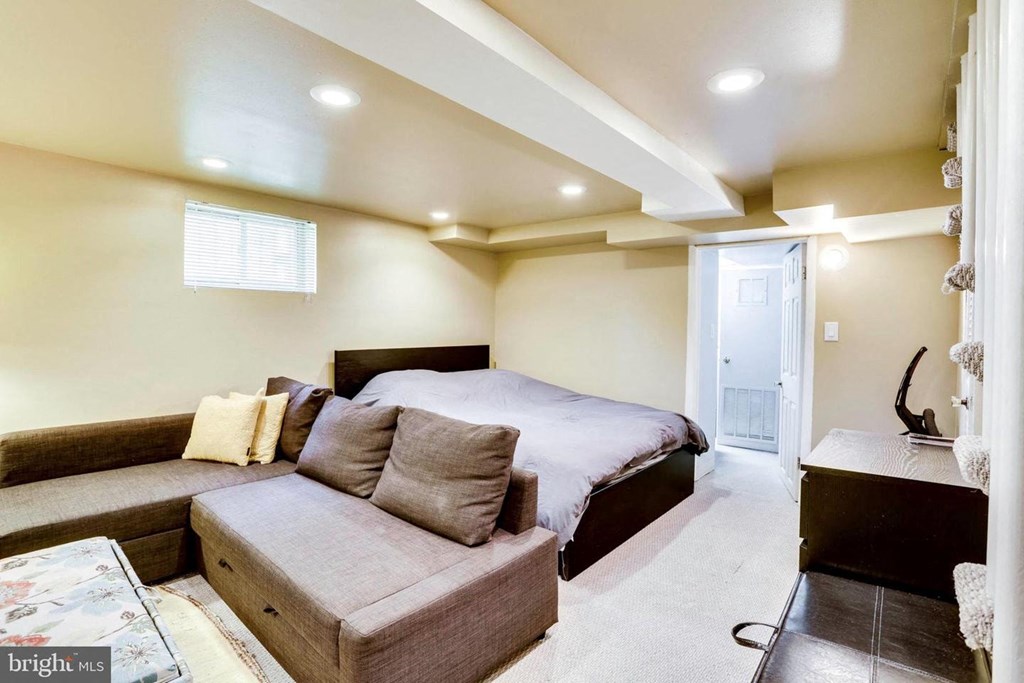 A bedroom with a bed, couch, and a window.