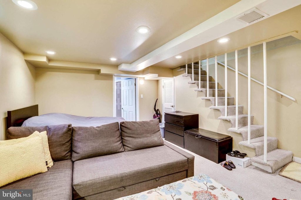 A living room with a grey couch and a staircase in the background.