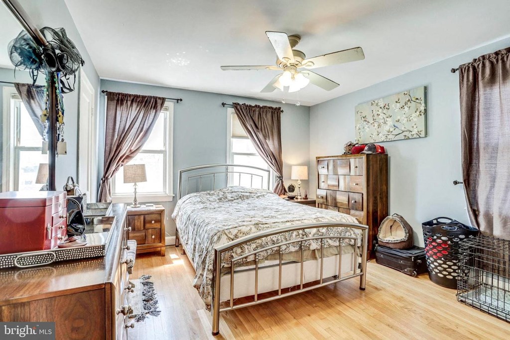 A bedroom with a bed, dresser, and window with curtains.