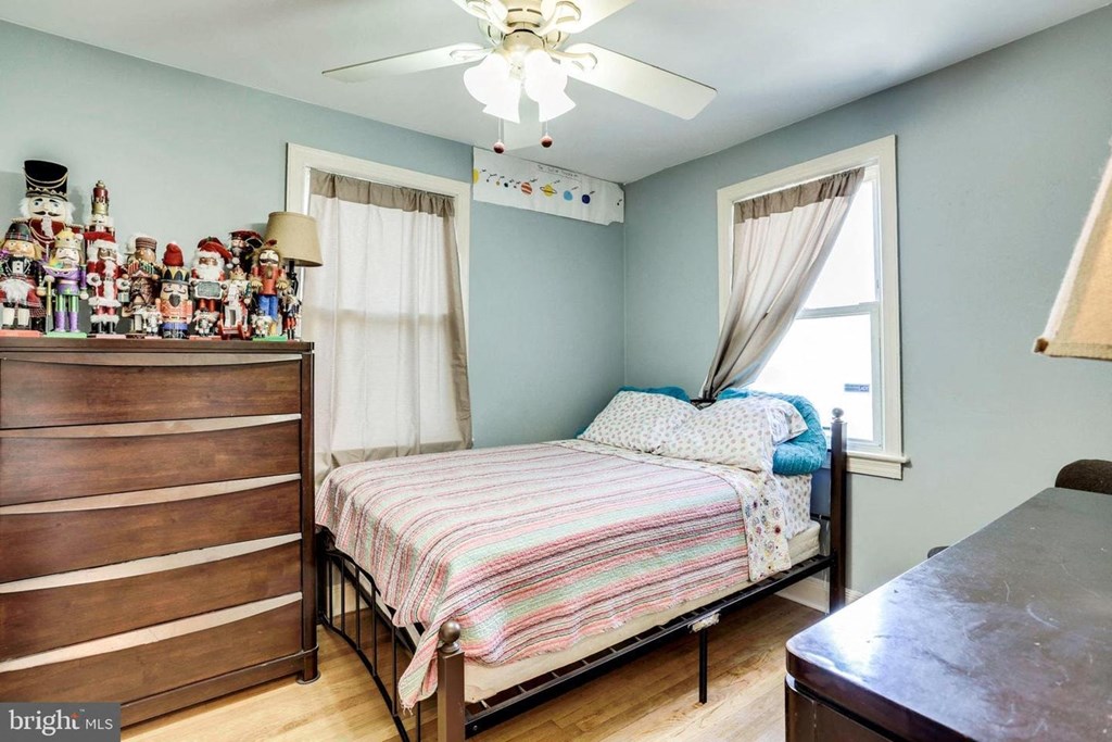 A bedroom with a bed, dresser, and a ceiling fan.